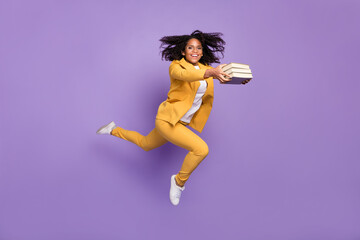 Photo of charming pretty lady wear yellow suit glasses smiling jumping high holding books isolated purple color background