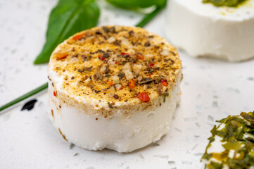 Cheese collection, variety of fresh white soft goat French cheeses with aromatic herbs, berries and green pesto