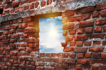 Ruined old brick building with broken window with sun, sky and cloudscape