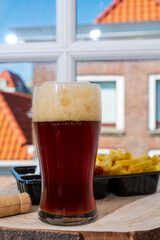 Drinking dark beer with fried cod fish fillet and french fried potatoed chips with view on street in old Zierikzee town, Zeeland, Netherland