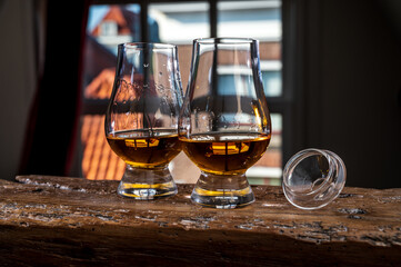 Dram of single malt scotch whisky served in tasting glass with view on old window and houses