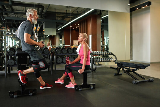 Professional aged trainer consulting mature woman in gym