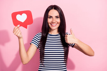 Portrait of attractive cheerful woman showing thumbup cool web media chat holding like card isolated over pink pastel color background