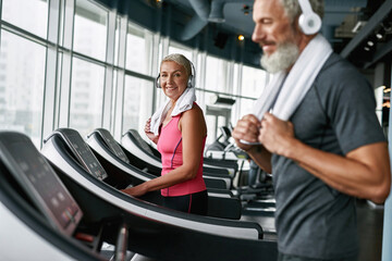 Healthy lifestyle concept. Mature woman working out on treadmill