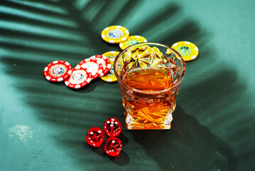 Hard strong alcoholic drinks in glass: cognac, tequila, scotch, brandy or whiskey on a green background with hard lights and shadows, top view.