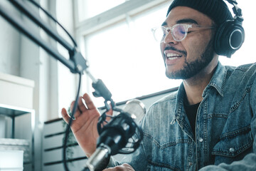 Handsome mixed race content creator streaming his audio show at cozy home studio using professional microphone and laptop