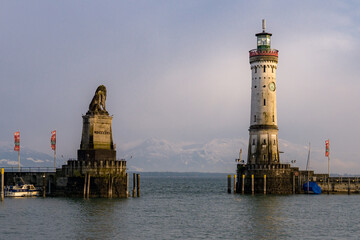 Fototapeta na wymiar lighthouse and lion at largest german lake with mountains in the background at day 