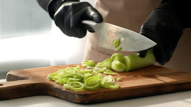 Female Cook Cutting Leeks With Knife Cooking In Kitchen, Closeup