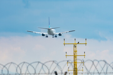 Aircraft landing on the airstrip of Milan Airport, Italy. Wings, fuselage and engine are visible. Blue sky and white clouds in the background.