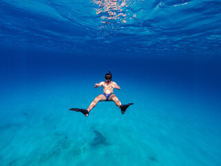 Obraz na płótnie Canvas Underwater photo of man free diving in clear sea