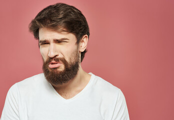 Fototapeta premium bearded man in a white t-shirt expressive look discontent pink background