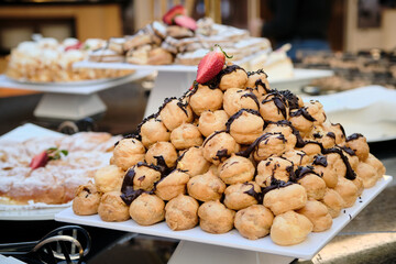 Buffet de dulces profiterol con sirope de chocolate y fresa