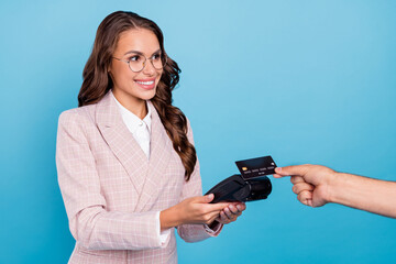 Portrait of attractive cheerful woman seller using bank card terminal customer service isolated over bright blue color background