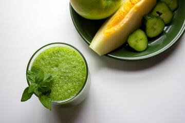 Batido de manzana, pepino, y melón,  saludable para el desayuno, acompañado de los ingredientes necesarios para prepararlo