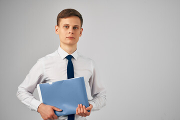 man in shirt with tie blue folder in hands gray background