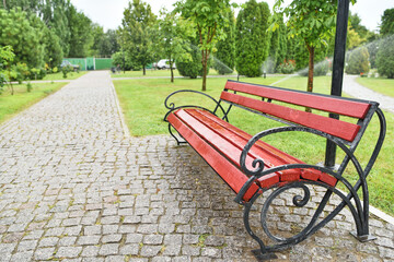 Wet garden bench red-brown with wrought iron armrests