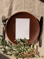 Empty craft handmade clay plate white card mockup linen tablecloth. Table place hand crafted dish.Natural cottagecore styled tableware minimal home interior decor.Restaurant food countryside aesthetic