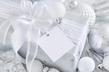 Christmas present with blank gift tag and white decorations, Mockup