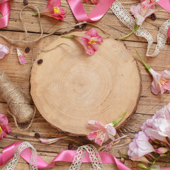 Flat lay of pink flowers and wooden board with copy space on wooden table