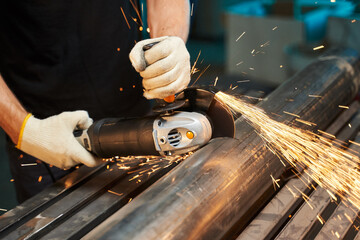 angle grinder for cutting metal, stones and ceramics. male hands in gloves cut a piece of iron pipe...