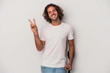 Young caucasian man with crutches isolated on gray background joyful and carefree showing a peace symbol with fingers.