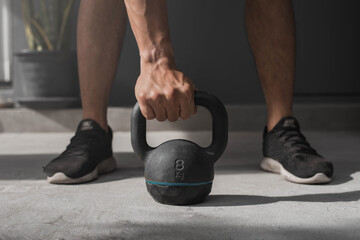 Kettlebell on the floor. Close-up of a muscular hand holding a kettlebell.