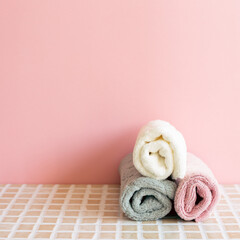 Bathroom towel on mosaic tile table. pink wall background. Skin care and spa concept. Home interior