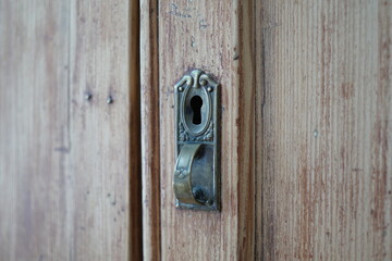 old metal handle with key hole
 of wooden closet door