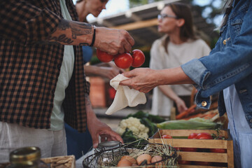 Close up of woman buying organic vegetables outdoors at local farmers market.
