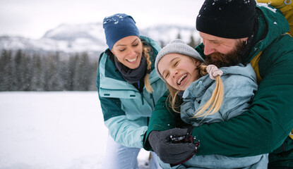 Family with small daughter hugging outdoors in winter nature