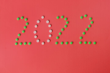 Christmas, New Year flat lay on blue background. numbers 2022 making with pills and medical mask. Top view. Copy space. Mock up. Concept of health care. New normal life after COVID-19. Copy space.