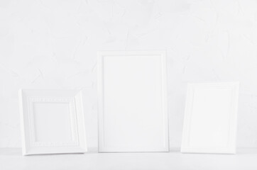 Home decor with blank white different wooden frames standing on wood desk in delicate soft light minimal modern white interior. Template for presentation, portfolio, message, text, design.