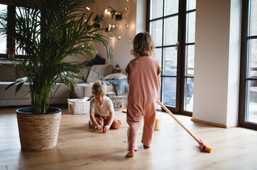 Two small children sweeping at home, daily chores concept.