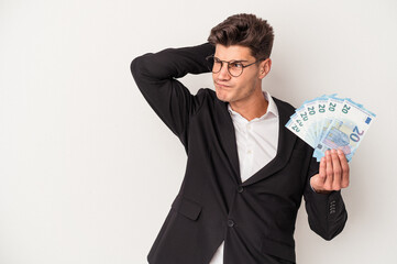 Young business caucasian man holding banknotes isolated on white background touching back of head, thinking and making a choice.
