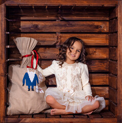 Beautiful cute girl child in a wooden square location in Christmas decorations