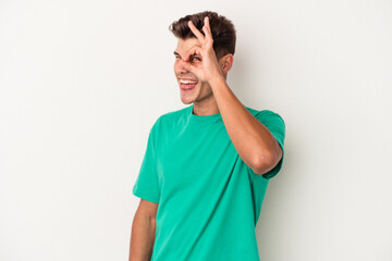 Young caucasian man isolated on white background excited keeping ok gesture on eye.