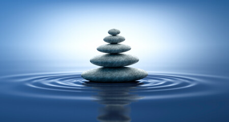 Obraz na płótnie Canvas Stack of stones with ripples in the water with blue reflections - zen and nature concept