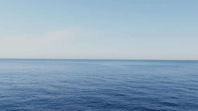 Blue endless sea water with bright sky and horizon, aerial fly forward view