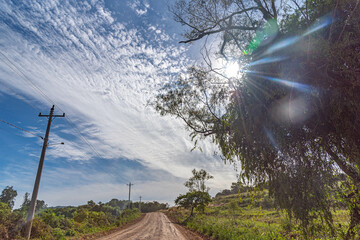 Dirt road in a rural area and the sky with clouds in the background