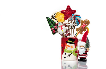 Winter concept with New Year decorations and sweets is isolated on a white background. Christmas festive card with Santa Claus, Christmas gingerbread and candy on sticks.