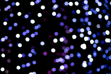 Christmas bokeh overlay background. Blue and violet lights on the black background. New Year, festive atmosphere