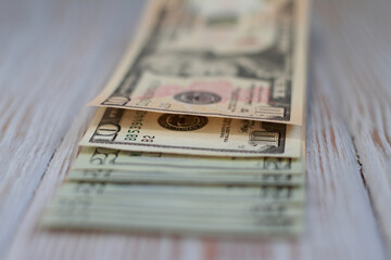 Ten and twenty dollar bills on a wooden light background. Shallow depth of field