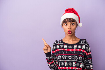 Fototapeta na wymiar Young mixed race woman celebrating Christmas isolated on purple background pointing to the side