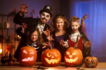 Young caucasian family mother father and children in Halloween costumes and makeup making scary gesture, saying trick or treat while celebrating together all hallows eve in dark room at home - obrazy, fototapety, plakaty