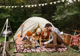 Gelukkige glimlachende familie die schaakspel speelt op de camping tijdens een kampeertrip in de natuur