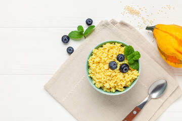 Millet porridge with pumpkin and berries in a bowl on the table. Baby food. Healthy breakfast. Copy space. Top view