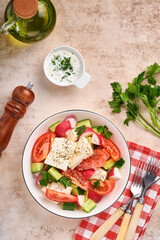 Radish, cucumber, tomato, pepper and feta cheese with spices pepper and olive oil in white bowl on grey slate, stone or concrete background. Healthy food concept. Top view.