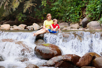 Family with child at waterfall. Travel with kids.