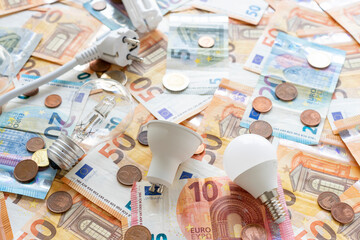 Electricity costs: Various types of light bulbs and electric socket on a background of euro...