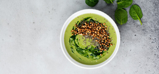 Useful smoothies from spinach with buckwheat flakes in ceramic bowls on gray concrete table background. Selective focus. Top view. Copy space